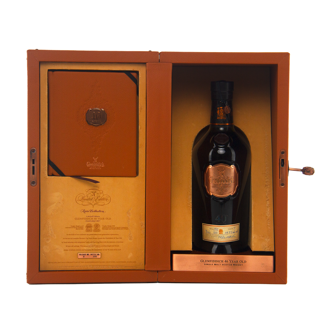 A luxurious leather box displays a limited edition Glenfiddich 40 Year Old Single Malt Scotch Whisky bottle with a gold label and seal on the right, and an embossed certificate or booklet on the left.
