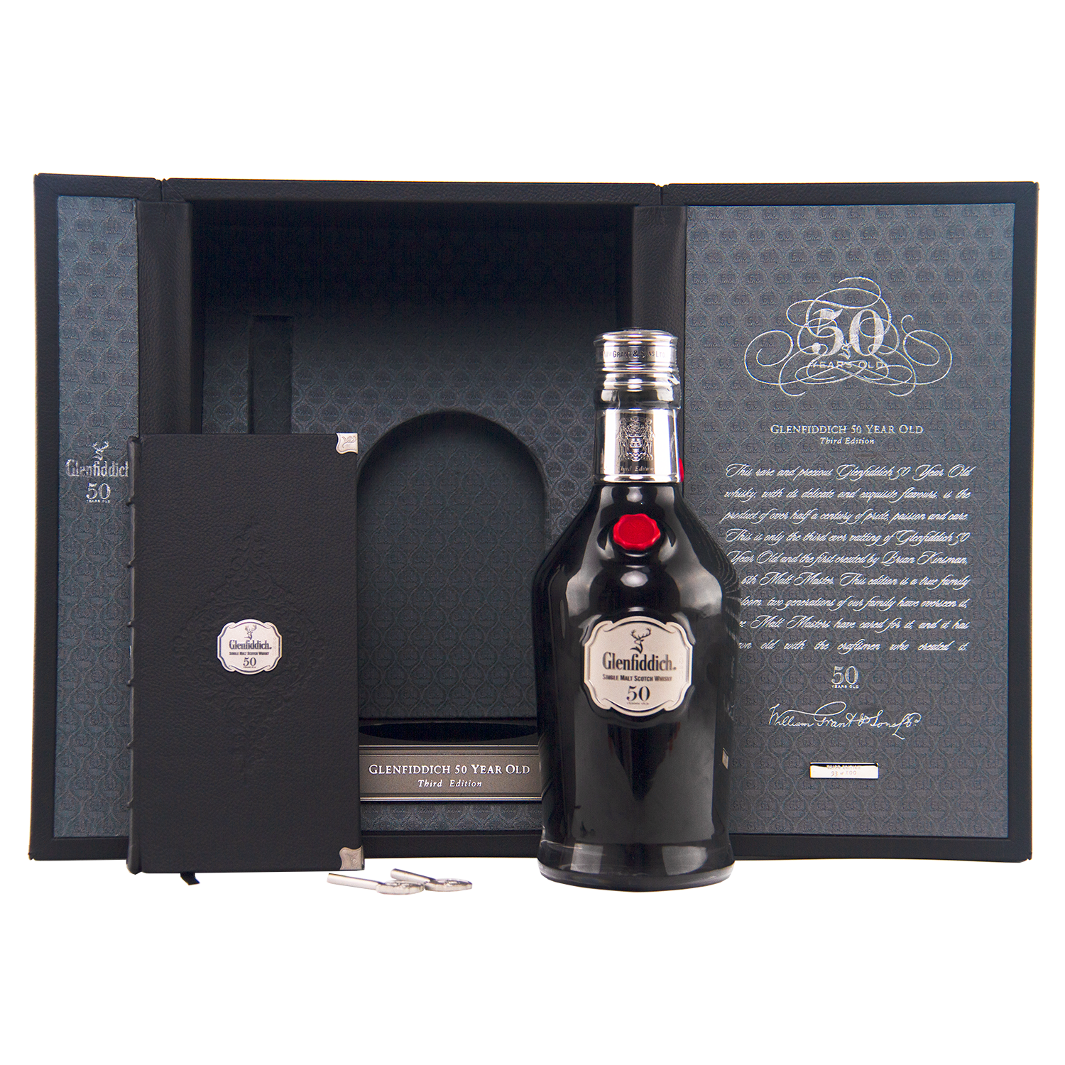 The Glenfiddich 50 Year Old Single Malt Scotch Whisky (Third Edition) is presented before an open display case, alongside a booklet, silver key, and certificate celebrating its extraordinary age and distinguished heritage.
