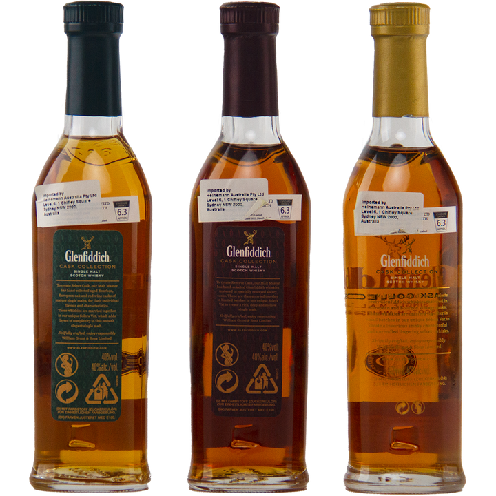 Three Glenfiddich Cask Collection Single Malt Scotch Whisky 200ml bottles with green, dark red, and gold labels are lined up with their backs showing ingredient and recycling details, the amber liquid hinting at the rich flavors inside.