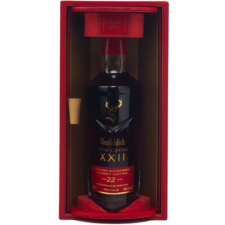 A bottle of Glenfiddich Gran Cortes XXII Single Malt Scotch Whisky, finished in rare Palo Cortado casks, comes in a striking red and gold display box with gold lettering and a stag logo on the dark bottle.