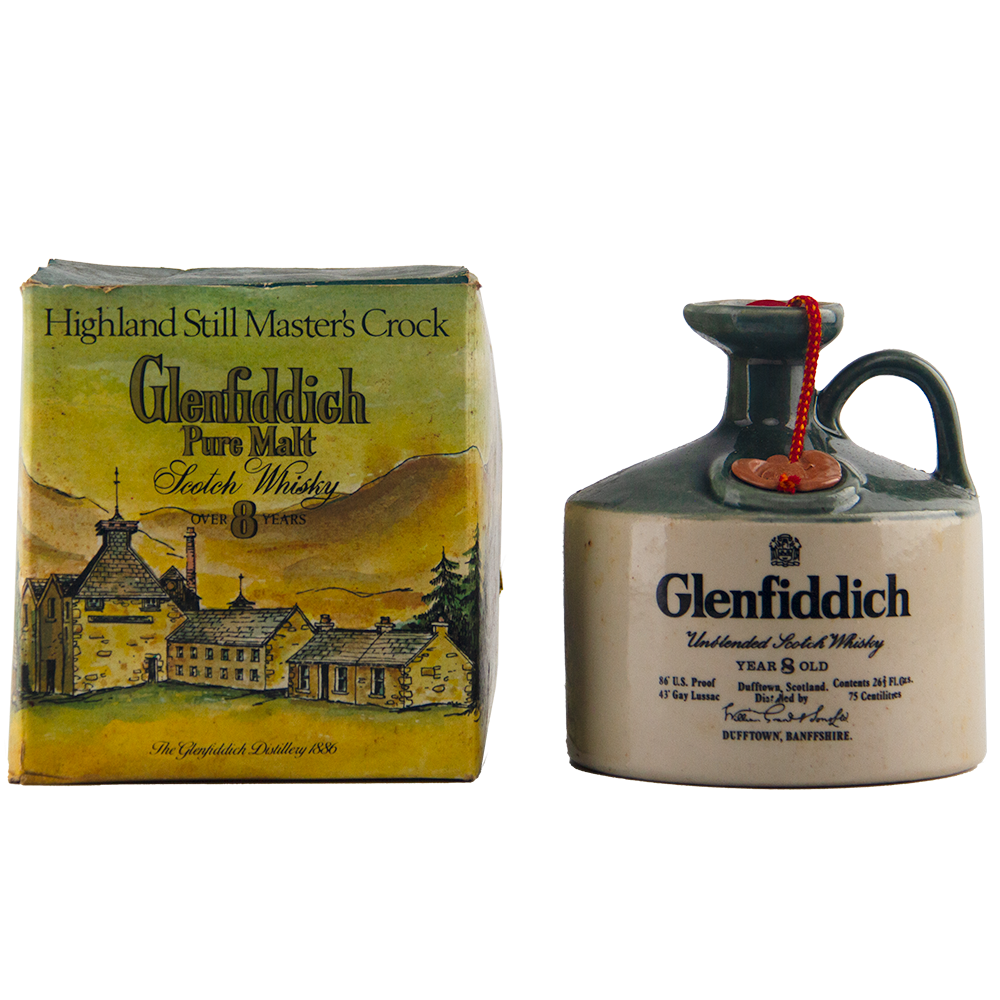 A Glenfiddich 8 Year Old Still Master’s Crock Decanter 1970 Single Malt Scotch Whisky, with handle and red seal, stands beside its illustrated “Highland Still Master’s Crock” box—a true collectible for whisky enthusiasts.
