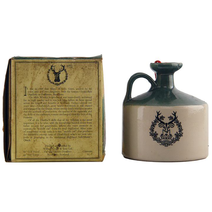 The Glenfiddich 8 Year Old Still Master’s Crock Decanter 1970, a collectible single malt whisky with green top, handle, and stag emblem, stands beside its original box showcasing matching text and logo.