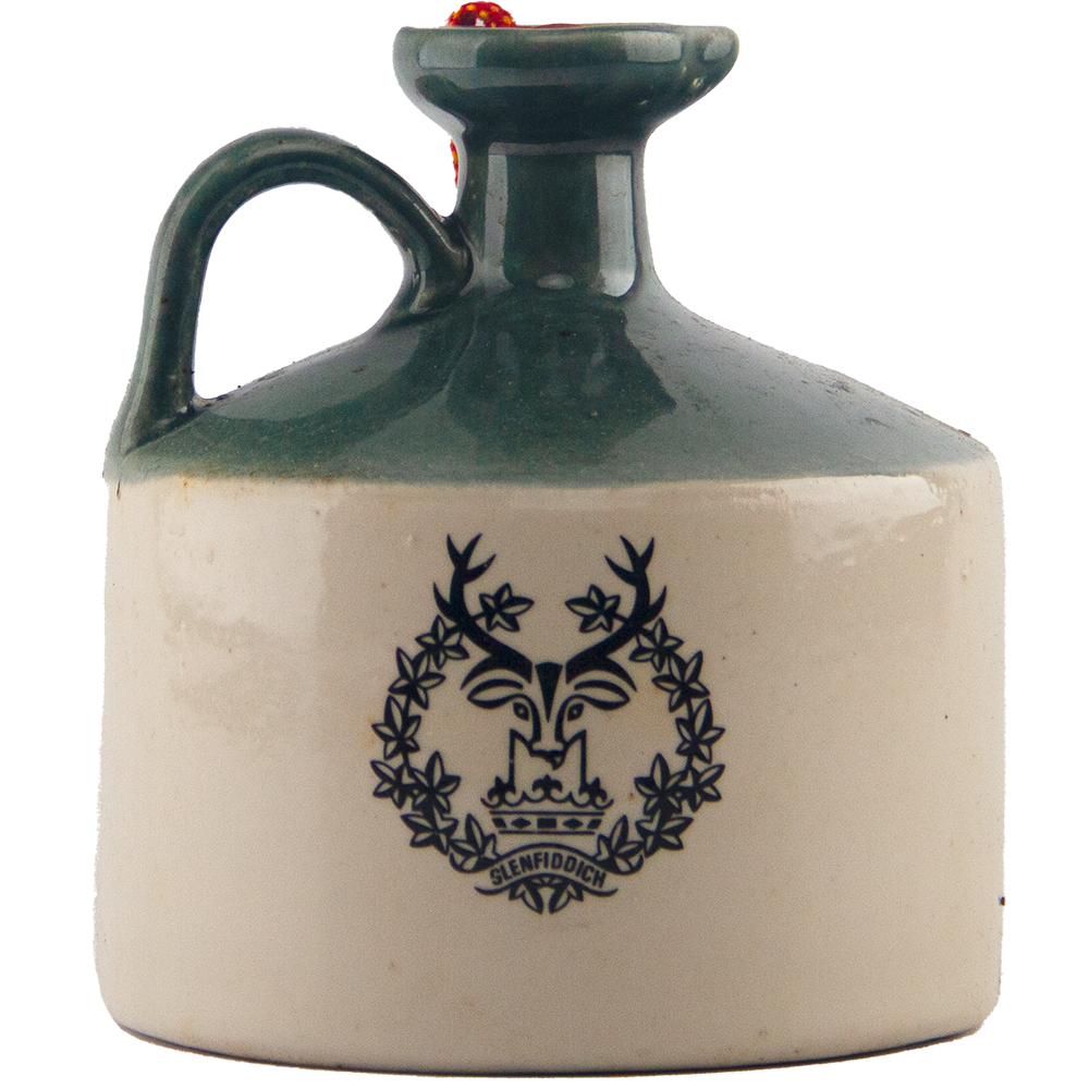 A collectible Glenfiddich 8 Year Old Still Master’s Crock Decanter from 1970, this ceramic jug with green handle and rim features a black stag head logo, wreath, and Glenfiddich branding—ideal as a single malt Scotch whisky decanter.