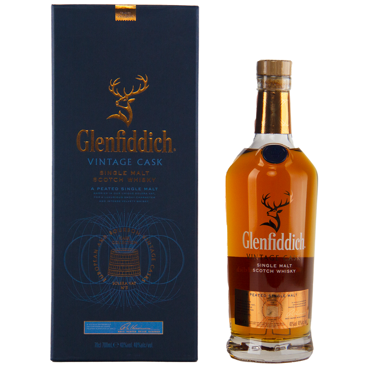 A bottle of Glenfiddich Vintage Cask Single Malt Scotch Whisky stands beside its blue and gold box adorned with a gold stag logo—this travel retail exclusive is an ideal choice for collectors.