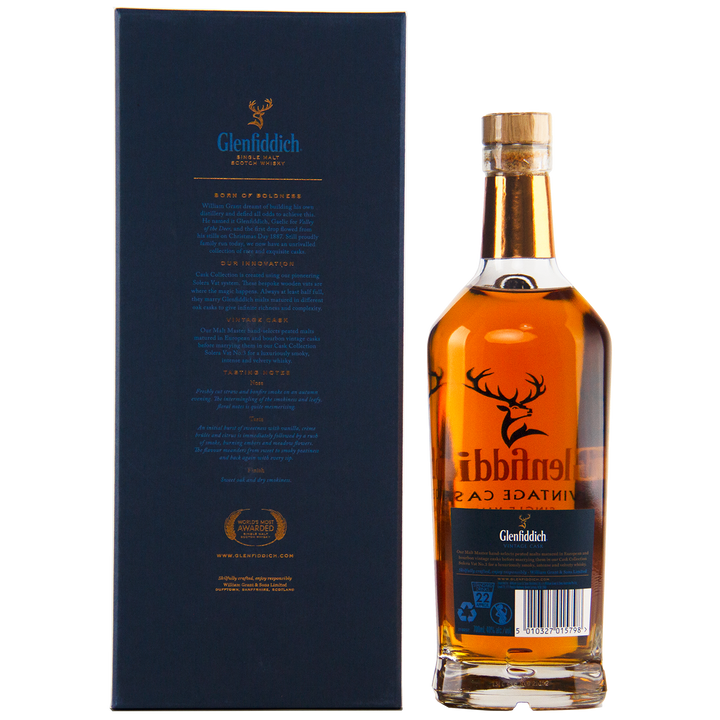 A bottle of Glenfiddich Vintage Cask Single Malt Scotch Whisky stands next to its dark blue box, both adorned with gold and white text and the iconic stag logo. This travel retail exclusive features a rich amber color.