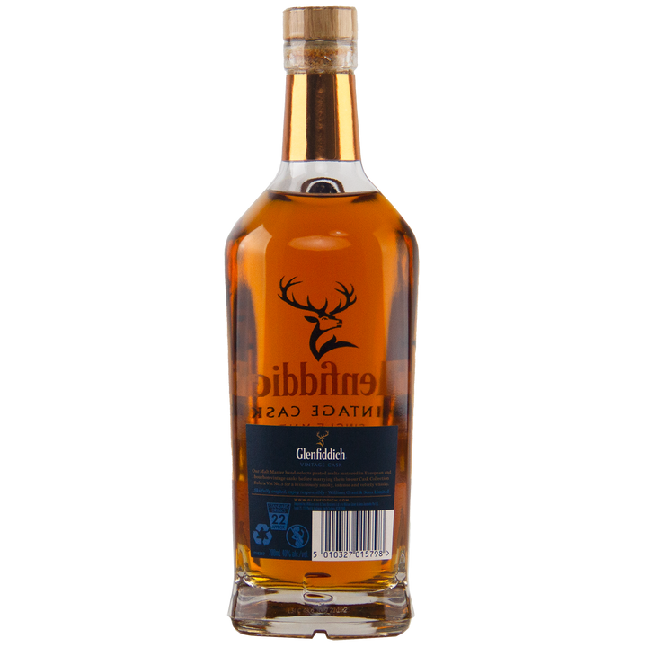 A bottle of Glenfiddich Vintage Cask Single Malt Scotch Whisky, shown from the back, reveals its amber liquid through clear glass with a label, barcode, and stag logo—this travel retail exclusive enhances any collection.