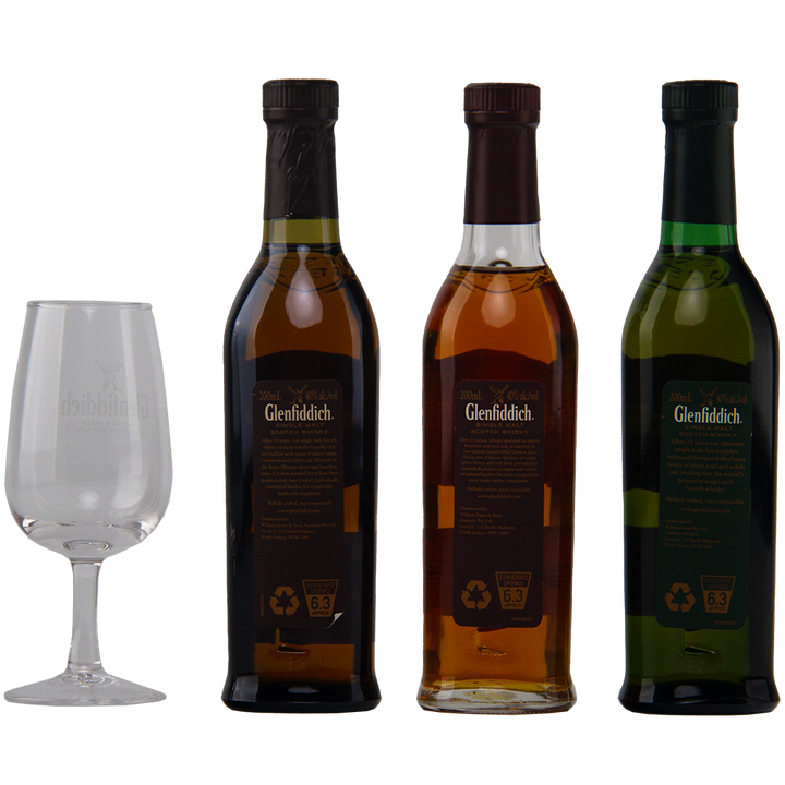 Three bottles of Glenfiddich Explorers Collection Single Malt Scotch Whisky 200ml, each with a different colored liquid, are arranged beside an empty Glenfiddich-branded glass on a plain white background.