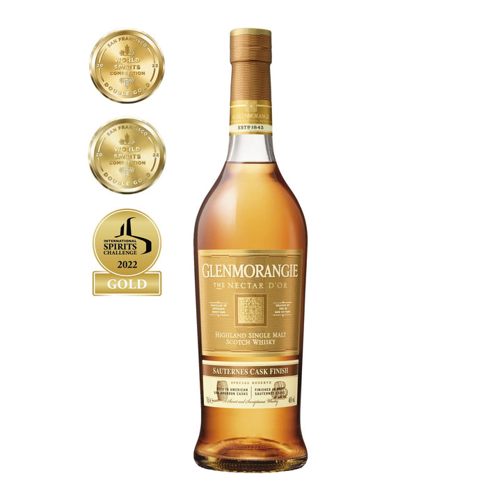 A bottle of Glenmorangie Nectar D’or Sauternes Cask Finish Single Malt Scotch Whisky stands beside three gold award medals, showcasing its acclaimed Sauternes cask finish and recognition in spirits competitions.