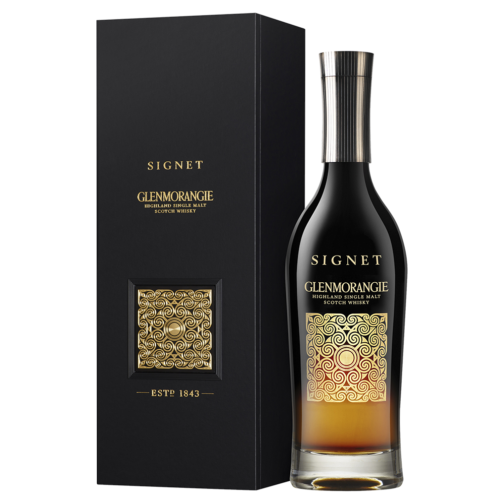 A bottle of Glenmorangie Signet Single Malt Scotch Whisky, made with chocolate malt, showcases a sleek black and gold label and is presented next to its matching black and gold box.