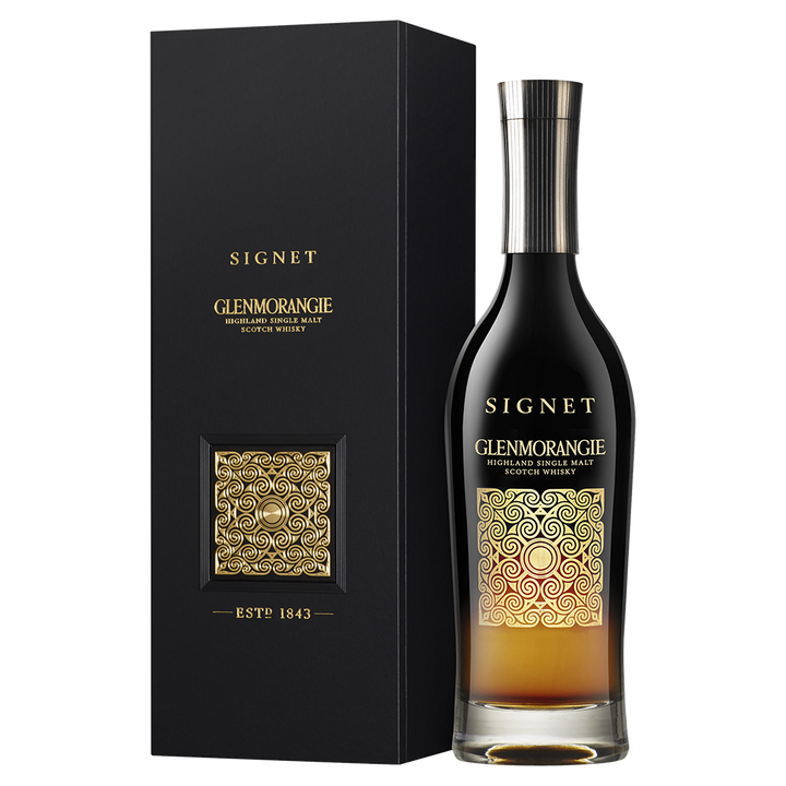 A bottle of Glenmorangie Signet Single Malt Scotch Whisky, made with chocolate malt, showcases a sleek black and gold label and is presented next to its matching black and gold box.