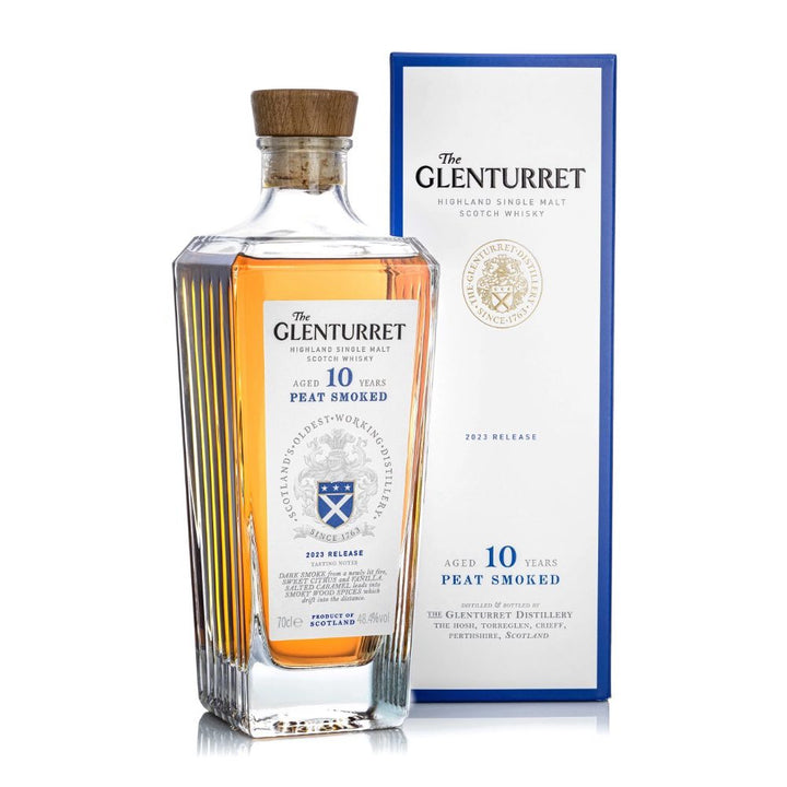 A bottle of Glenturret 10 Year Old Peat Smoked Single Malt Scotch Whisky with an angular shape and wooden cap is displayed beside its blue and white box packaging.