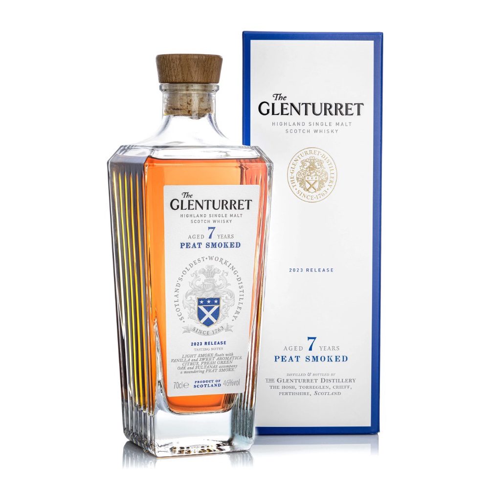 A bottle of Glenturret 7 Year Old Peat Smoked Single Malt Scotch Whisky stands before its blue and white box, amber liquid shining beneath the cork. Both label and box feature the brand's crest.