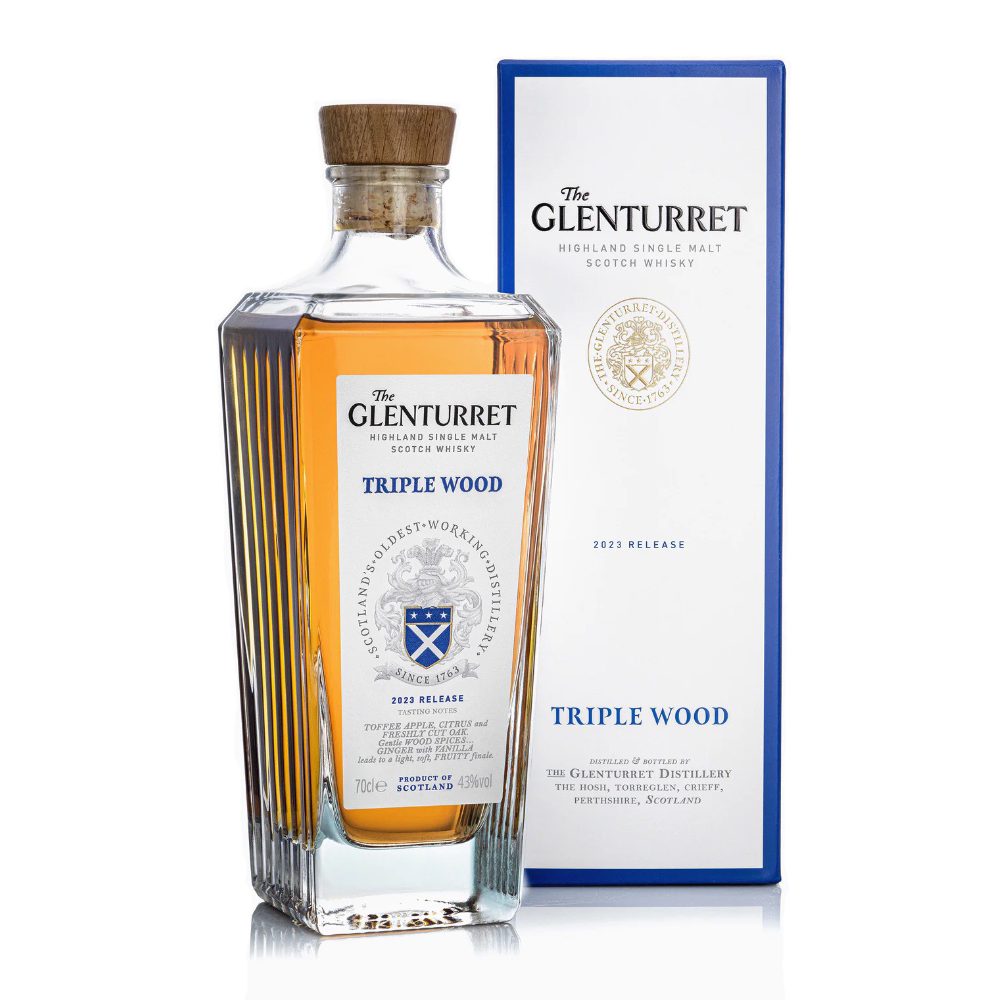 A bottle of Glenturret Triple Wood Single Malt Scotch Whisky stands before its blue and white box with a crest; the golden amber spirit highlights rich depth from three-cask maturation.
