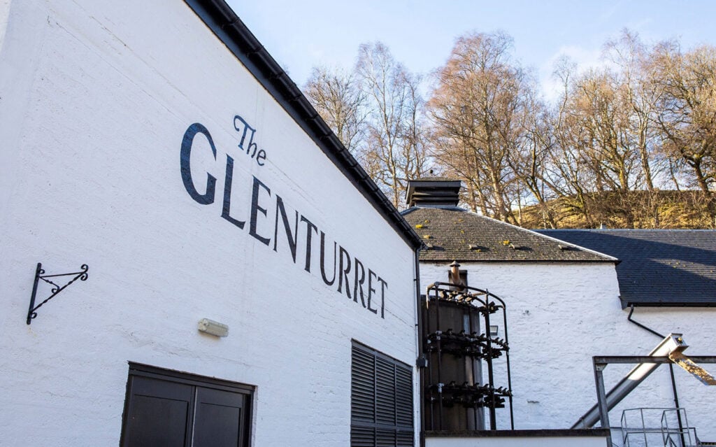 White building with 'The Glenturret' branding, surrounded by trees on a sunny day.