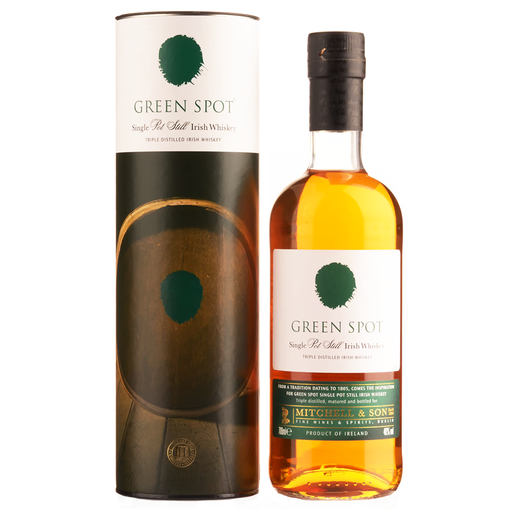A bottle of Green Spot Single Pot Still Irish Whiskey stands next to its cylindrical packaging, both featuring white labels with a green spot logo and gold and green accents. The bottle contains golden amber whiskey.