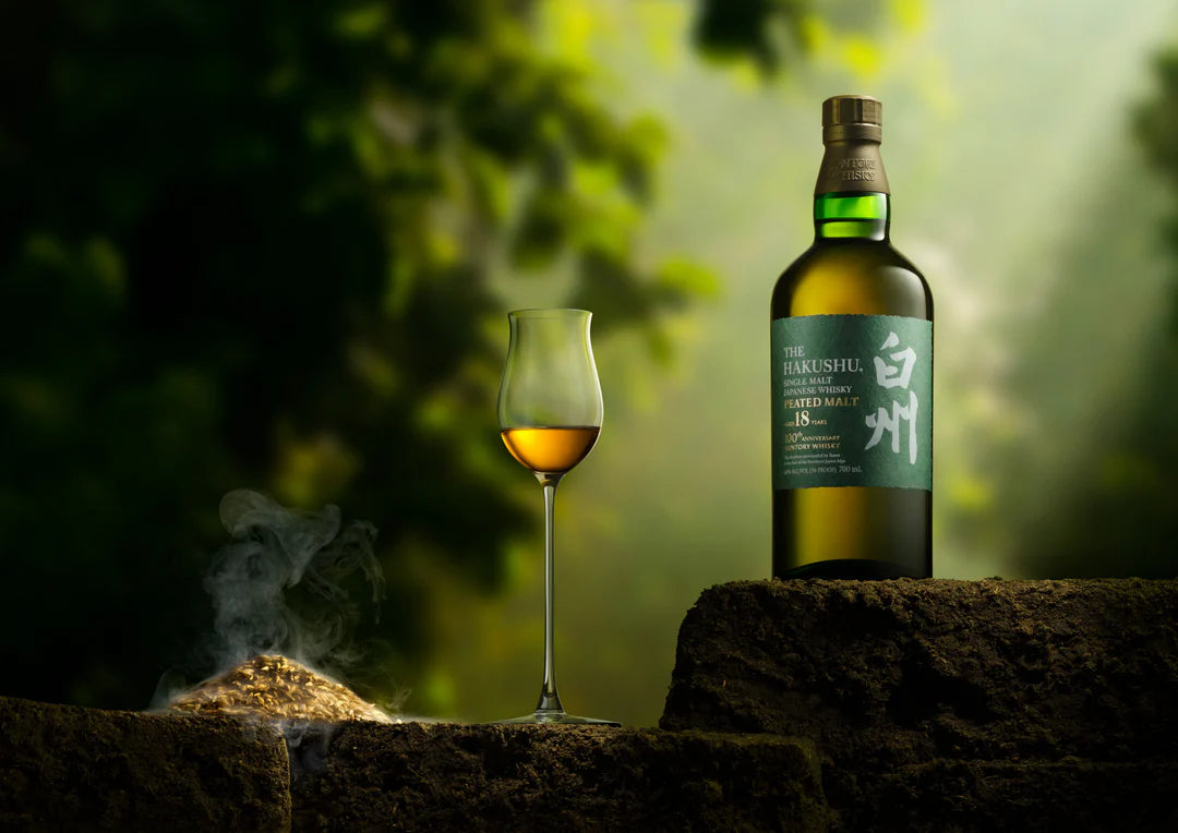 Bottle and glass of whisky on a stone surface with a natural background