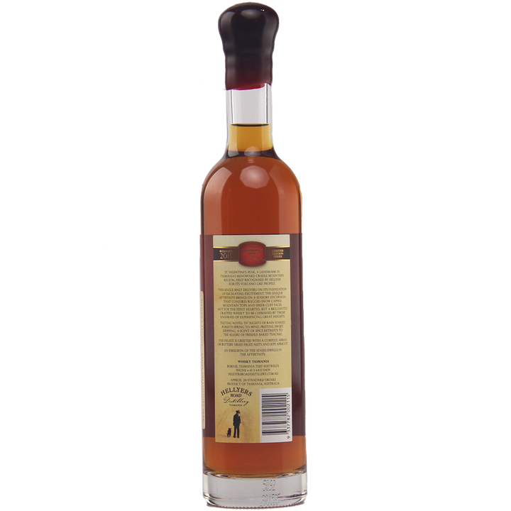 A tall bottle of amber Hellyers Road Saint Valentines Peak Australian Single Malt Whisky, capped with black wax, is shown from the back with a tan label featuring text, barcode, and a small logo at the bottom.