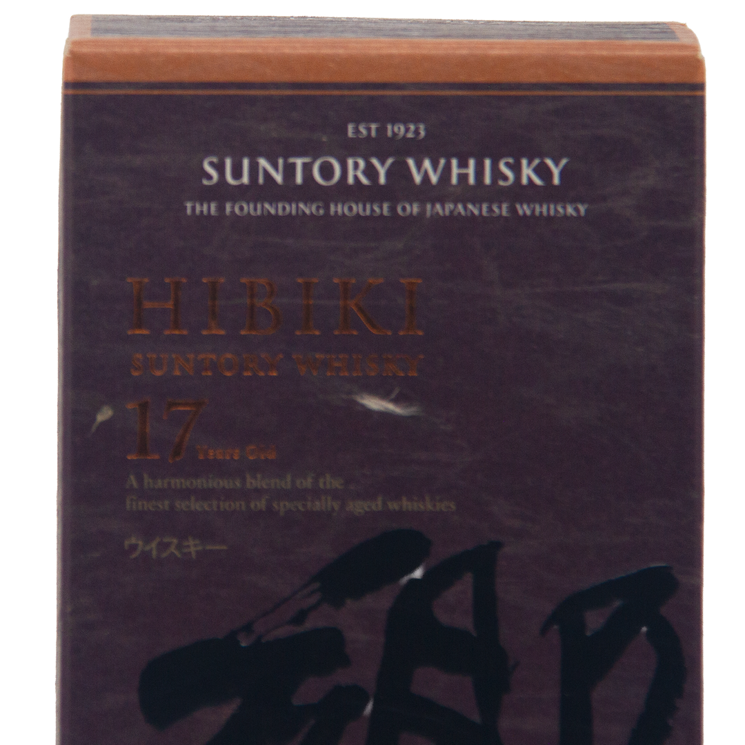 A close-up of a Hibiki 17 Year Old Japanese Blended Malt Whisky box shows gold and white text with the whisky’s name, age, and description highlighted on a dark background.