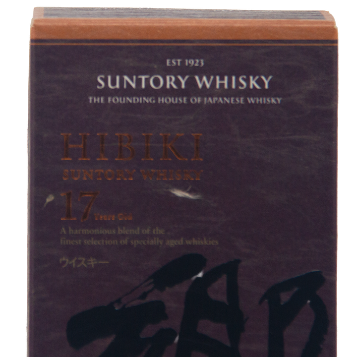 A close-up of a Hibiki 17 Year Old Japanese Blended Malt Whisky box shows gold and white text with the whisky’s name, age, and description highlighted on a dark background.