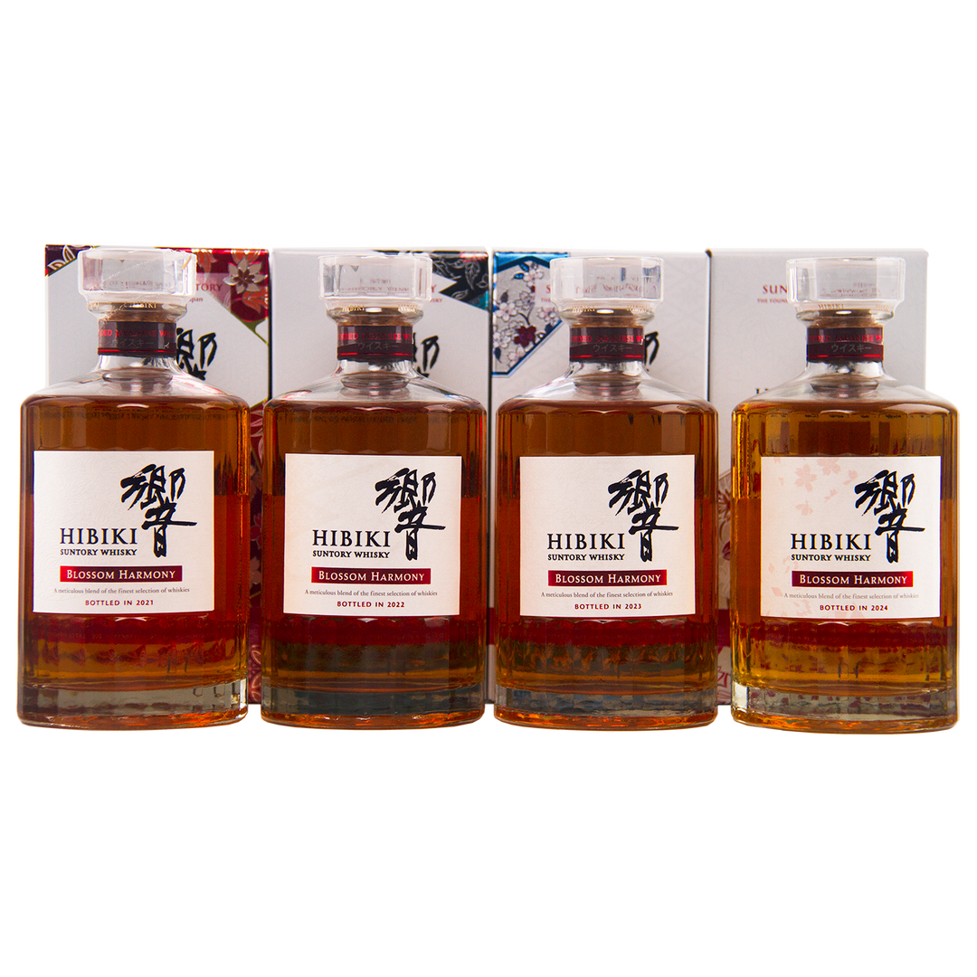 Four bottles from the Hibiki Blossom Harmony Limited Edition Collection 2021 to 2024 are displayed with their decorative boxes, each featuring a clear stopper and a striking white label—an exquisite Suntory release.