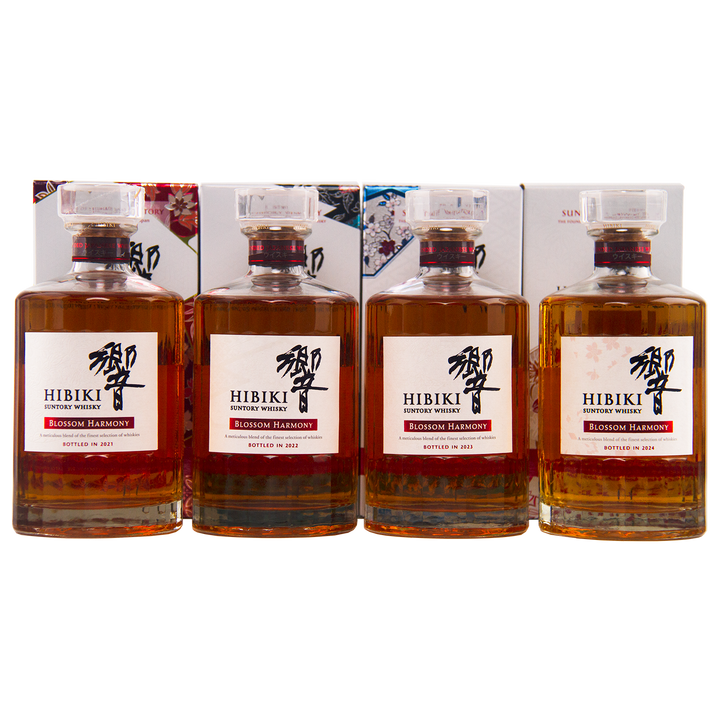 Four bottles from the Hibiki Blossom Harmony Limited Edition Collection 2021 to 2024 are displayed with their decorative boxes, each featuring a clear stopper and a striking white label—an exquisite Suntory release.