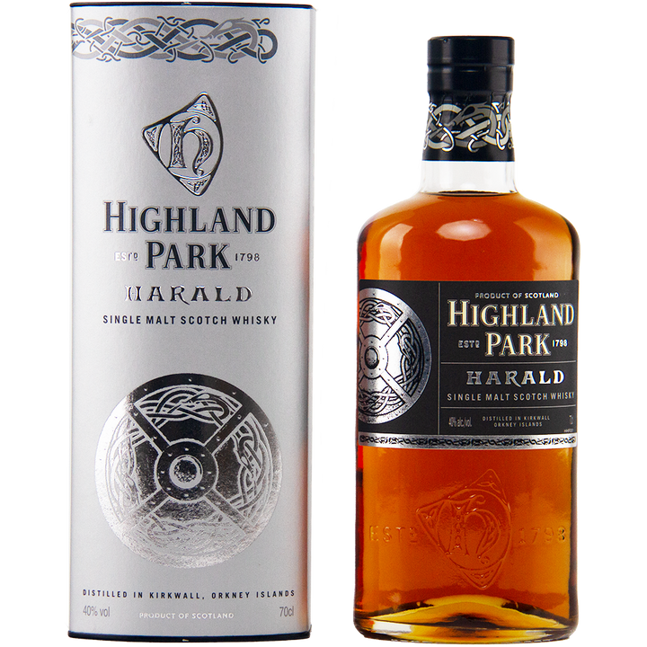 A bottle of Highland Park Harald Single Malt Scotch Whisky stands beside its matching silver cylindrical box, both adorned with Celtic designs and black, silver, and gold labels inspired by sherry-seasoned oak casks.
