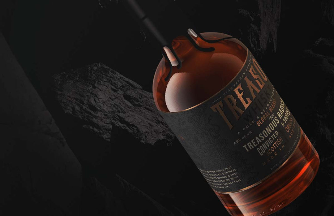A close-up of the Highwayman Treacherous Radicals Single Malt Australian Whisky bottle, tilted against a dark, rocky backdrop with amber liquid showing and the label's intricate details partially visible.