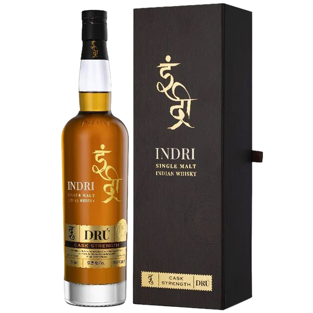 A bottle of Indri Drú Cask Strength Single Malt Indian Whisky stands beside its matching dark box. The bottle’s gold and white label complements the box, which displays gold text and a logo in both English and Hindi script.