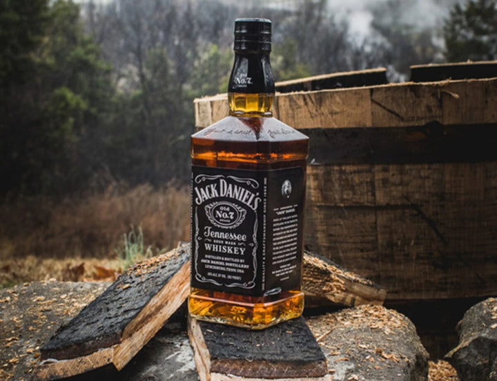 Jack Daniel's Tennessee Whiskey bottle on a wooden barrel with a forest background