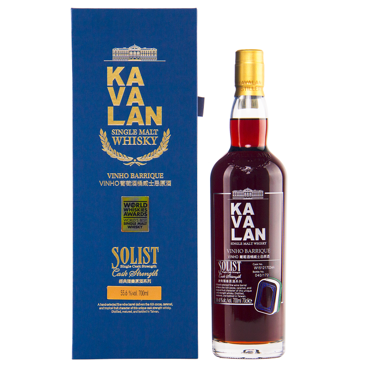 A bottle of Kavalan 2015 Vinho Barrique Cask No. W151217034A Taiwanese whisky stands beside its blue and gold box, showing award labels and English-Chinese text. The dark amber single malt gleams through the bottle.