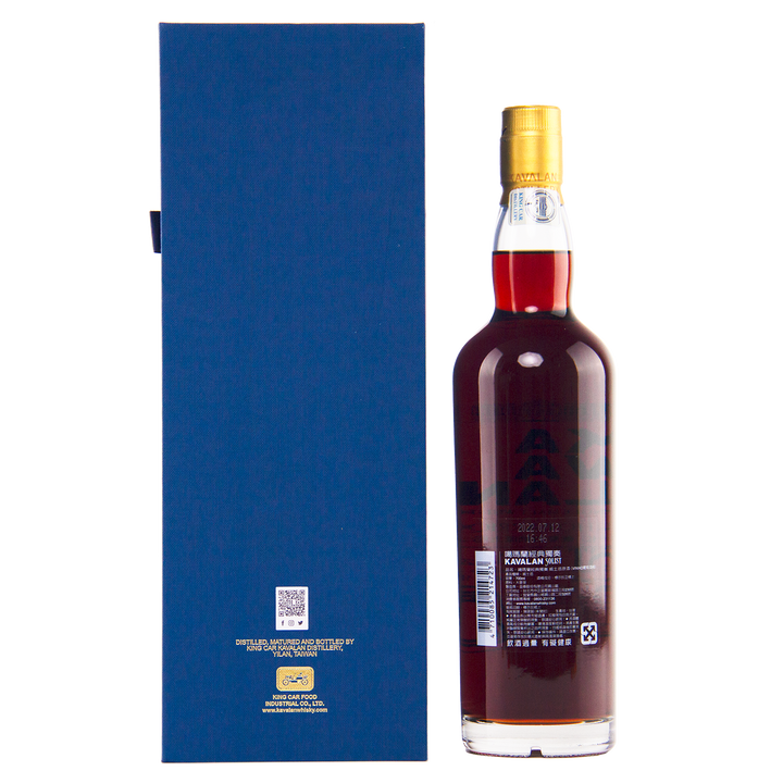 A bottle of dark amber Kavalan 2015 Vinho Barrique Cask No. W151217034A whisky with a gold cap stands beside a tall blue rectangular box displaying text and a QR code, both set against a plain white background.