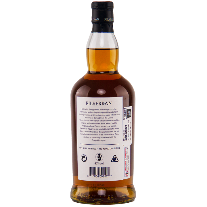A bottle of Kilkerran 12 Year Old Single Malt Scotch Whisky is shown from the back, featuring a white label with text, barcodes, and symbols. The amber whisky and black cap display distinctive Glengyle Distillery branding.