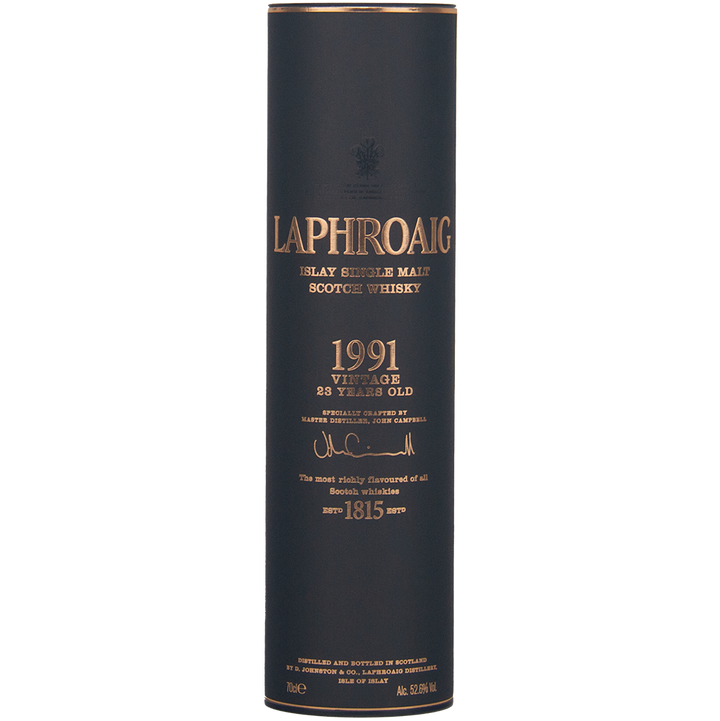 A cylindrical dark box with gold text houses the Laphroaig 1991 Vintage 23 Year Old Single Malt Whisky, featuring collector’s edition branding that highlights its heritage, quality, and cask strength.