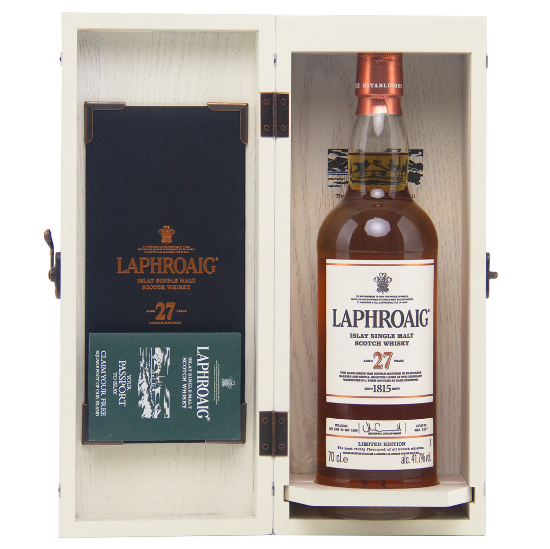 A bottle of Laphroaig 27 Year Old Single Malt Whisky is presented in an open wooden box with branded packaging and a Passport booklet—an elegant, investment-worthy choice for whisky collectors.