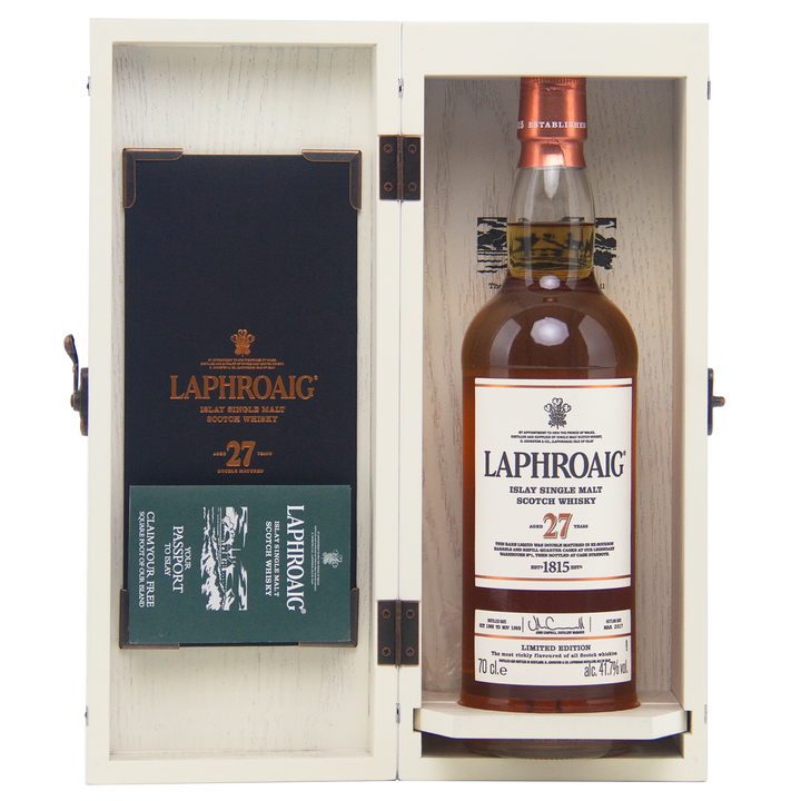 A bottle of Laphroaig 27 Year Old Single Malt Whisky is presented in an open wooden box with branded packaging and a Passport booklet—an elegant, investment-worthy choice for whisky collectors.