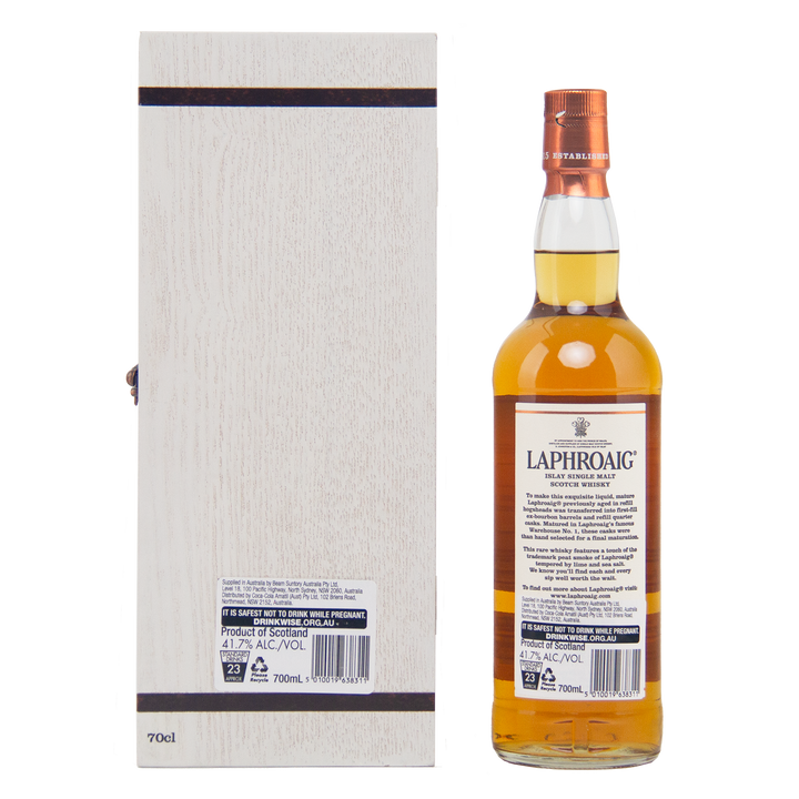 A bottle of Laphroaig 27 Year Old Single Malt Whisky with a copper cap stands beside its tall, light wooden box, both shown from the back to highlight their investment-grade labels and detailed packaging.