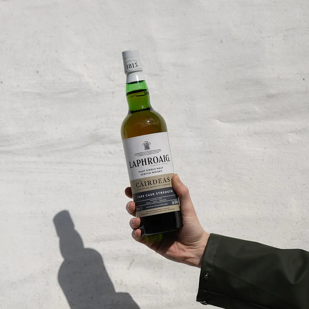 Hand holding a bottle of Laphroaig whisky against a light background