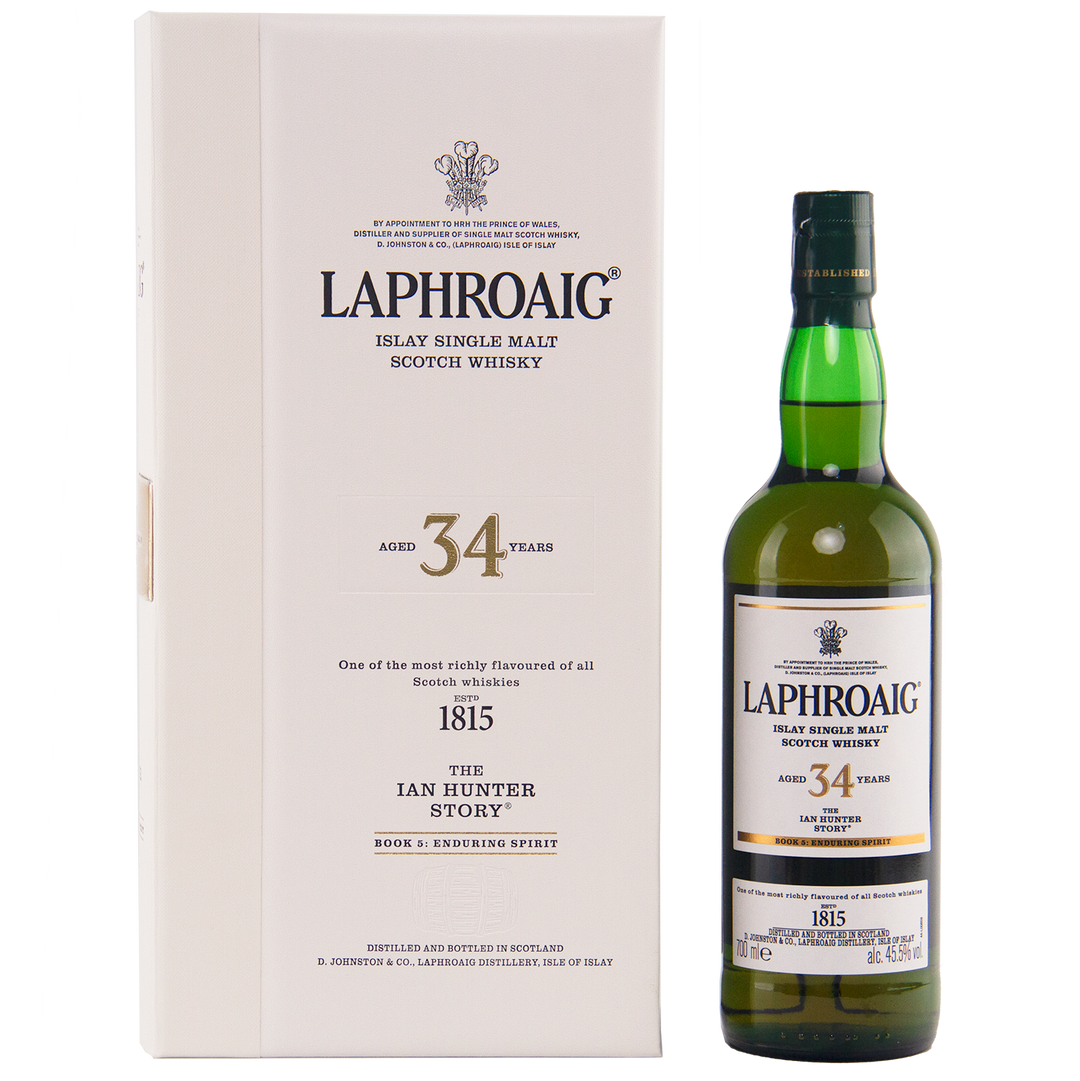 A bottle of Laphroaig Ian Hunter Story Book 5 34 Year Old Single Malt Whisky stands next to its white box, both featuring black and gold text that highlights the exceptional heritage and character of this 34-year-old Islay malt.