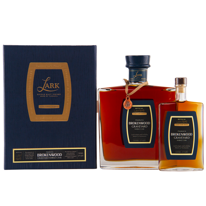 Two bottles of Lark Brokenwood Graveyard Shiraz Rare Cask Single Malt Whisky, one large and one small, with square bodies and black-gold labels, are displayed beside a dark blue and gold gift box bearing the product name.