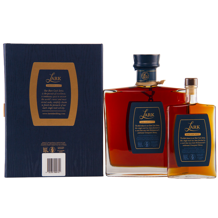 Two bottles of Lark Brokenwood Graveyard Shiraz Rare Cask Single Malt Whisky stand beside a navy blue box. The amber Tasmanian whisky features gold-accented navy labels from the Rare Cask Series.