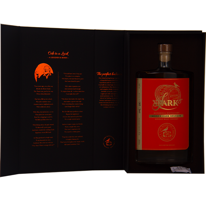 A large bottle of Lark Monty Cask Release Single Malt Whisky, with a red and gold label, is displayed in an open black box. The inside cover has orange text and a small illustration describing this limited edition whisky.