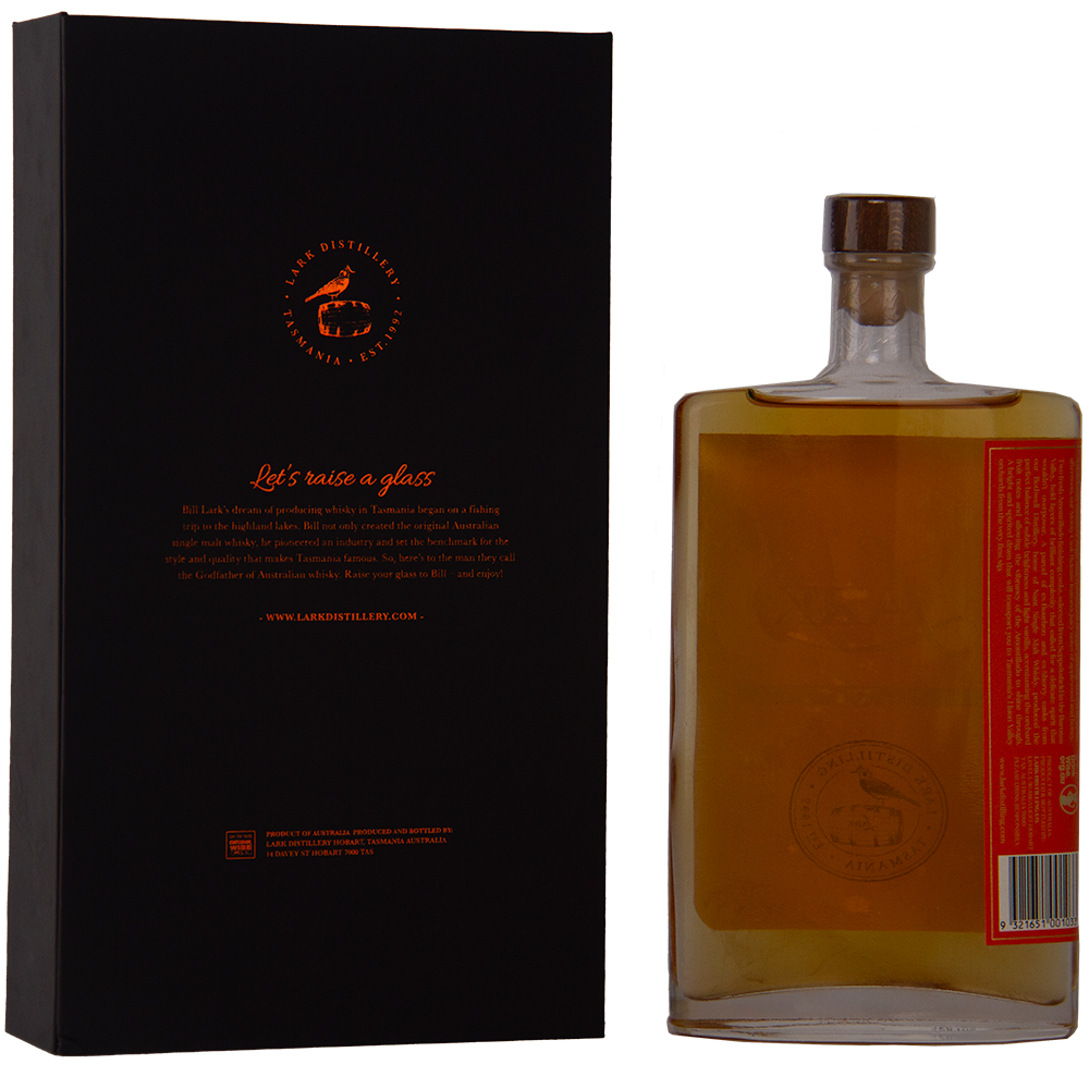 A rectangular bottle of Lark Monty Cask Release Single Malt Whisky with a wooden cap stands beside a black and orange box featuring the Lark logo. The amber whisky, matured in Amontillado cask, features a minimalist label and limited edition appeal.
