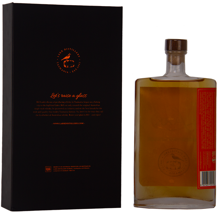 A rectangular bottle of Lark Monty Cask Release Single Malt Whisky with a wooden cap stands beside a black and orange box featuring the Lark logo. The amber whisky, matured in Amontillado cask, features a minimalist label and limited edition appeal.