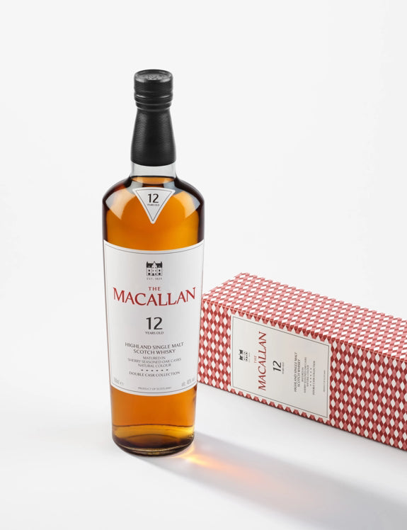A bottle of The Macallan Double Cask 12 Year Old Single Malt Scotch Whisky stands upright beside its red patterned box on a white background, highlighting the signature sherry-seasoned cask influence.