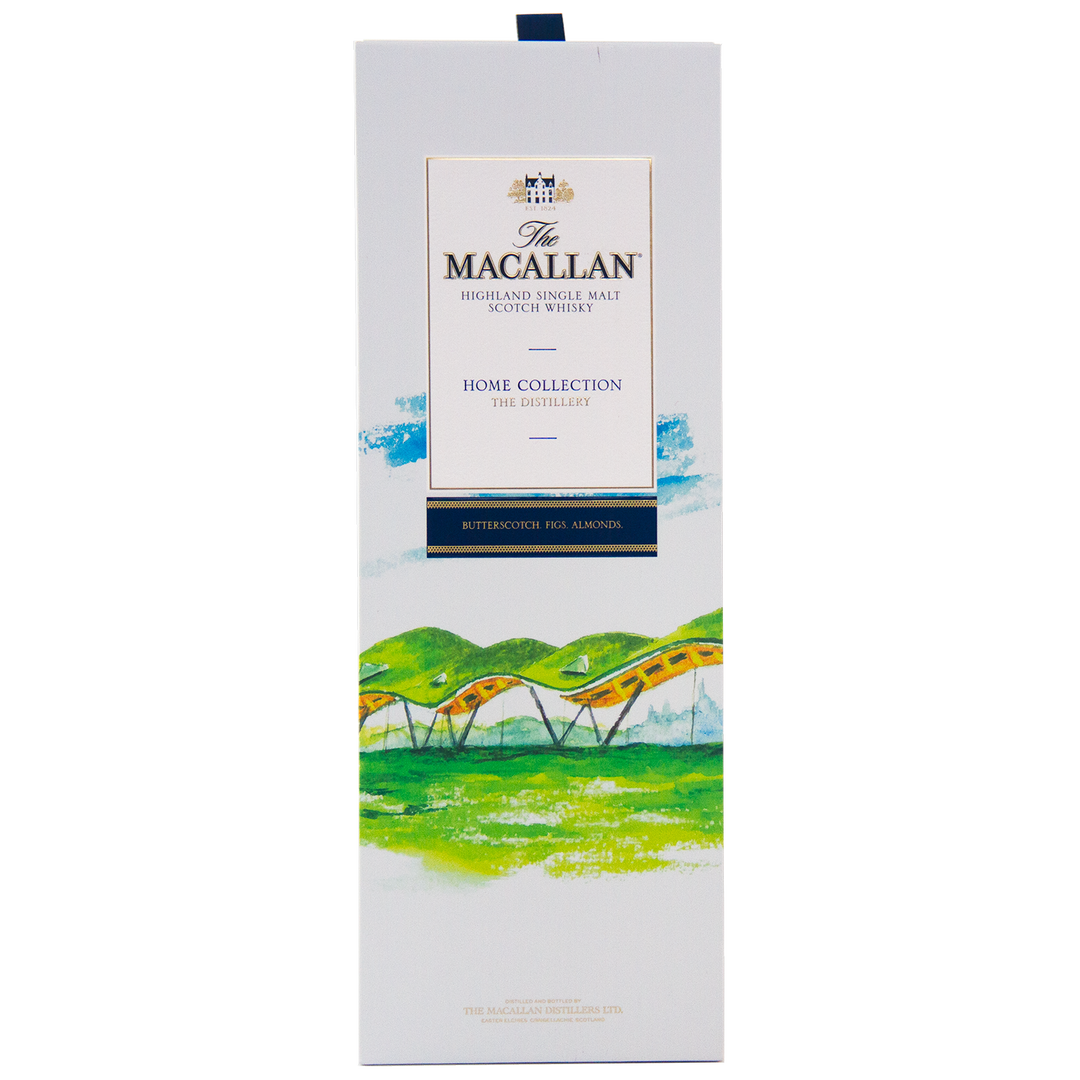 The image shows a rectangular white box of The Macallan Home Collection The Distillery Single Malt Scotch Whisky, featuring colorful landscape artwork with hills and a yellow bridge, highlighting its collectible nature.