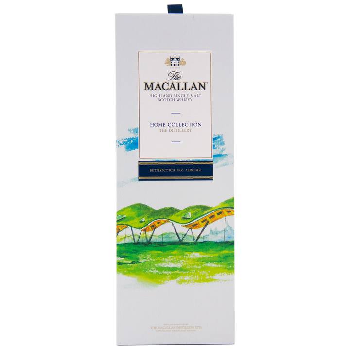 The image shows a rectangular white box of The Macallan Home Collection The Distillery Single Malt Scotch Whisky, featuring colorful landscape artwork with hills and a yellow bridge, highlighting its collectible nature.