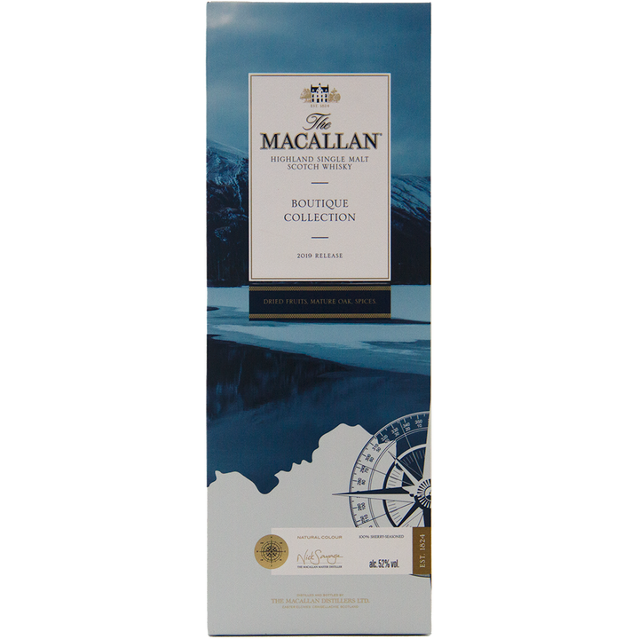 A rectangular box for The Macallan Boutique Collection 2019 Release Single Malt Whisky, adorned with blue and white mountain imagery, a whisky compass design, and gold and black text—emphasizing its travel retail exclusivity.