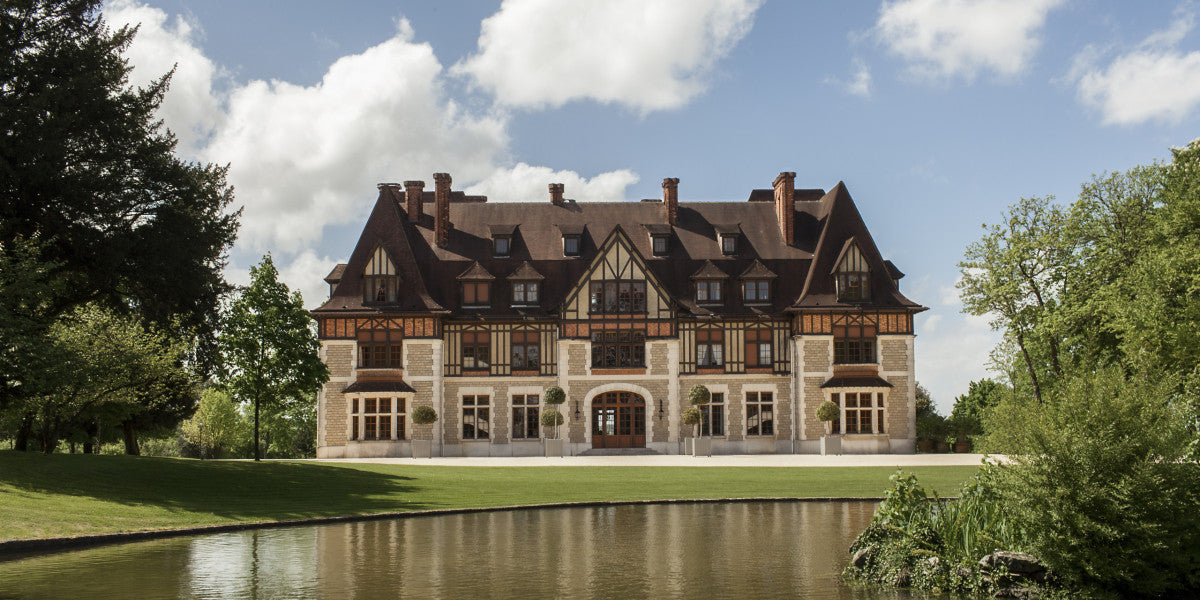 Large mansion with a pond in front on a sunny day