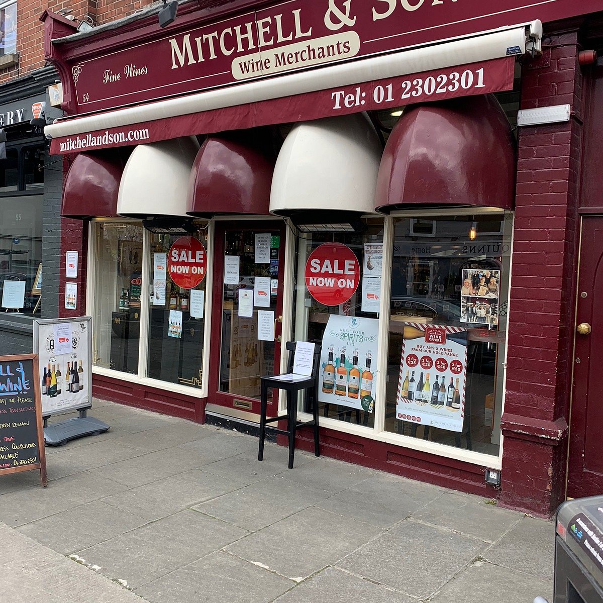 Mitchell & Sons Wine Merchants store front with sale signs in the window.
