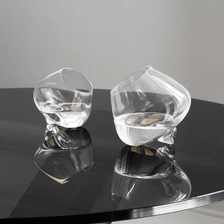 Two clear glass chairs on a reflective surface with a neutral background
